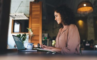 Caucasian female student with education textbook using laptop application for watching webinar while e learning at terrace, skilled woman with notepad checking browsed web information on netbook